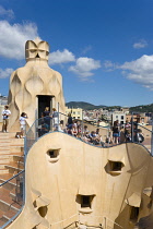 Spain, catalonia, Barcelona, Tourist visitors on the roof of Casa Mila apartment building known as La Pedrera or Stone Quarry designed by Antoni Gaudi in the Eixample district.