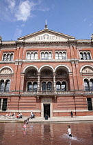 England, London, Kensington, Children splashing in fountain in Victoria and Albert Museum courtyard.