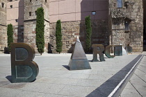 Spain, Catalonia, Barcelona,  scuplture by Joan Brossa in front of Barcelonas Roman wall, where the aqueduct once entered the city and spells out the word Barcino, the Roman name of Barcelona