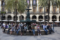 Spain, Catalonia, Barcelona, Tourists sat around the fountain in Placa Reial.