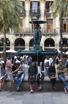 Spain, Catalonia, Barcelona, Tourists sat around the fountain in Placa Reial.