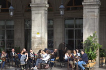 Spain, Catalonia, Barcelona, Tourists sat at tables outside cafe in Placa Reial.