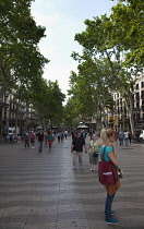 Spain, Catalonia, Barcelona, Tourist walking along the tree lined avenue of La Rambla.