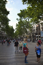 Spain, Catalonia, Barcelona, Tourist walking along the tree lined avenue of La Rambla.