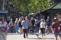 Spain, Catalonia, Barcelona, Tourist walking along the tree lined avenue of La Rambla.