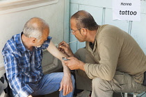 Turkey, Istanbul, Man having a henna tattoo tattooed onto his arm.