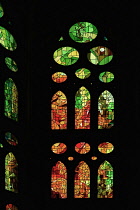 Spain, Catalunya, Barcelona, Basilica i Temple Expiatori de la Sagrada Familia, Colourful stained glass window details on the Passion Facade wing.