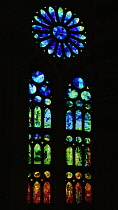 Spain, Catalunya, Barcelona, Basilica i Temple Expiatori de la Sagrada Familia, Colourful stained glass window details on the Passion Facade wing.