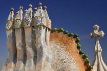 Spain, Catalunya, Barcelona, Antoni Gaudi's Casa Batllo building, colourful chimney pots on the roof terrace with the four armed cross also inclluded.