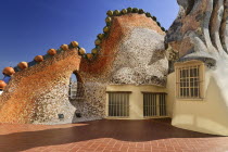 Spain, Catalunya, Barcelona, Antoni Gaudi's Casa Batllo building, detail of dragon's back tile feature on the roof terrace with windows included.