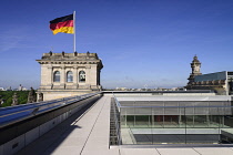 Germany, Berlin, German flag fluttering on a corner tower of the Reichstag building as seen from the rooftop terrace.