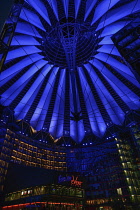 Germany, Berlin, Potzdamer Platz, Sony Centre with glass canopied roof over central plaza at night.