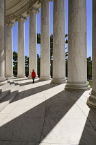 USA, Washington DC, National Mall, Thomas Jefferson Memorial, A tourist strolls among the Ionic columns with long shadows cast by evening sun.