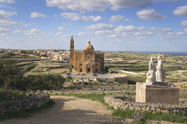 Malta, Gozo, Ta Pinu, Sanctuary church seen form hilltop with statues in the foreground.