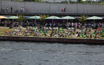 Germany, Berlin, Mitte, people sunbathing on the banks fo the river Spree.