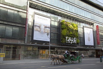 Germany, Berlin, Mitte, Vertical planting on the exterior of Galeries Lafayette on Friedrichstrasse with horse and carriage passing. **Editorial Use Only**