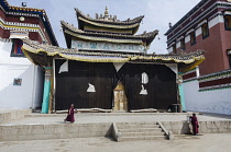 China, Tibet, Two young monks are working near the slightly decayed temple of Wutun Si monastery.