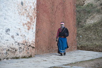 China, Tibet, Woman praying whilst moving around a temple at Labrang Monastery.