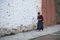 China, Tibet, Woman praying whilst moving around a temple at Labrang Monastery.