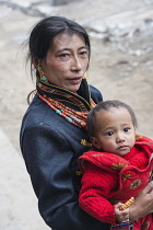China, Tibet, Gade City, Tibetan woman in national clothes with a child.