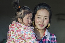 China, Tibet, Hot Spring city, Shy Tibetan woman is holding a child at a monastery in Madoi County.