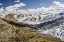 China, Tibet, Majestic high altitude landscape of snowy mountains and cloudy sky near Golod city.