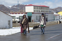 China, Tibet, Qingzhenxiang, Tibetans in national clothes at the street of high altitude city.