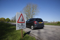 Transport, Road, Cars, resurfaced road with sign warning of reduced speed limit and loose chippings.