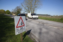 Transport, Road, Cars, resurfaced road with sign warning of reduced speed limit and loose chippings.