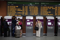 Spain, Madrid, Passengers using the self-service ticket machines in front of the departures board inside the terminus of the Atocha Railway Station