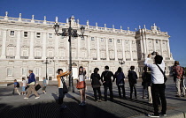 Spain, Madrid, Tourists pose for photographs in front of the Palacio Real.