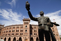 Spain, Madrid, Statue of a matador with the Plaza de Toros de las Ventas in the background
