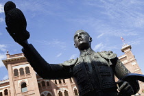 Spain, Madrid, Statue of a matador with the Plaza de Toros de las Ventas in the background.