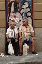 Spain, Madrid, Two visitors to the El Rastro Flea market take a rest from shopping.
