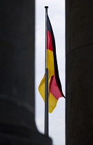 Germany, Berlin, Mitte, a black, red and yellow national flag hanging down from a flagpole outside the Reichstag building in Tiergarten.