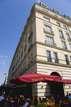 Germany, Berlin, Mitte, the rebuilt five star Hotel Adlon Kempinski on the corner of Unter den Linden and Pariser Platz with people at tables under umbrellas.