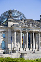 Germany, Berlin, Mitte, The Reichstag building in Tiergarten with the inscrption Dem Deucschen Volke, For the German People, on the facade above the columns at the entrance with Norman Foster's glass...