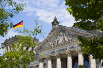 Germany, Berlin, Mitte, The Reichstag building in Tiergarten with the inscrption Dem Deucschen Volke, For the German People, on the facade above the columns at the entrance with German flag flying alo...