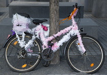 Germany, Berlin, Mitte, Holocaust Memorial with a bicycle decorated with pink and white ribbons leaning against a tree.
