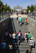 Germany, Berlin, Mitte, sightseeing tourists emerging from the U-Bahn and S-Bahn station on Unter den Linden and walking towards Brandenburg Gate or Bransenburger Tor.