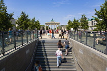 Germany, Berlin, Mitte, sightseeing tourists emerging from the U-Bahn and S-Bahn station on Unter den Linden and walking towards Brandenburg Gate or Bransenburger Tor.