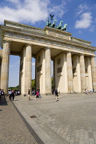 Germany, Berlin, Mitte, sightseeing tourists at the Brandenburg Gate or Bransenburger Tor in Pariser Platz leading to Unter den Linden and the Royal Palaces with the Quadriga of Victory on top. The on...