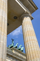 Germany, Berlin, Mitte, Brandenburg Gate or Bransenburger Tor seen between columns in Pariser Platz leading to Unter den Linden and the Royal Palaces with the Quadriga of Victory on top. The only rema...