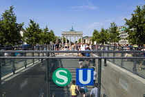 Germany, Berlin, Mitte, sightseeing tourists emerging from the U-Bahn and S-Bahn station on Unter den Linden and walking towards Brandenburg Gate or Bransenburger Tor.