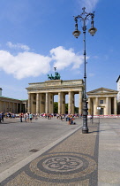 Germany, Berlin, Mitte, sightseeing tourists at the Brandenburg Gate or Bransenburger Tor in Pariser Platz leading to Unter den Linden and the Royal Palaces with the Quadriga of Victory on top. The on...