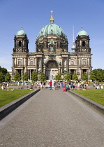 Germany, Berlin, Mitte, Museum Island. Berliner Dom, Berlin Cathedral. people cooling down in a fountain in Lustgarten in front of the church with copper green domes and the Fernsehturm TV Tower beyon...