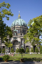 Germany, Berlin, Mitte, Museum Island. Berliner Dom, Berlin Cathedral, with green copper domes and people on the grass in Lustgarten.