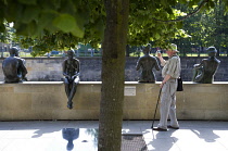 Germany, Berlin, Mitte, elderly man photographing bronze statues on the bank of the Spree River called Three Girls and a Boy, Drie Madchen und ein Knabe, by artist Wilfried Fitzenreiter.