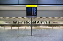 England, London, Heathrow Airport, deserted International Arrivals hall in Terminal 5 with electronic arrivals board listing incoming due flights.