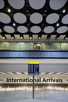 England, London, Heathrow Airport, deserted International Arrivals hall in Terminal 5 with electronic arrivals board listing incoming due flights.